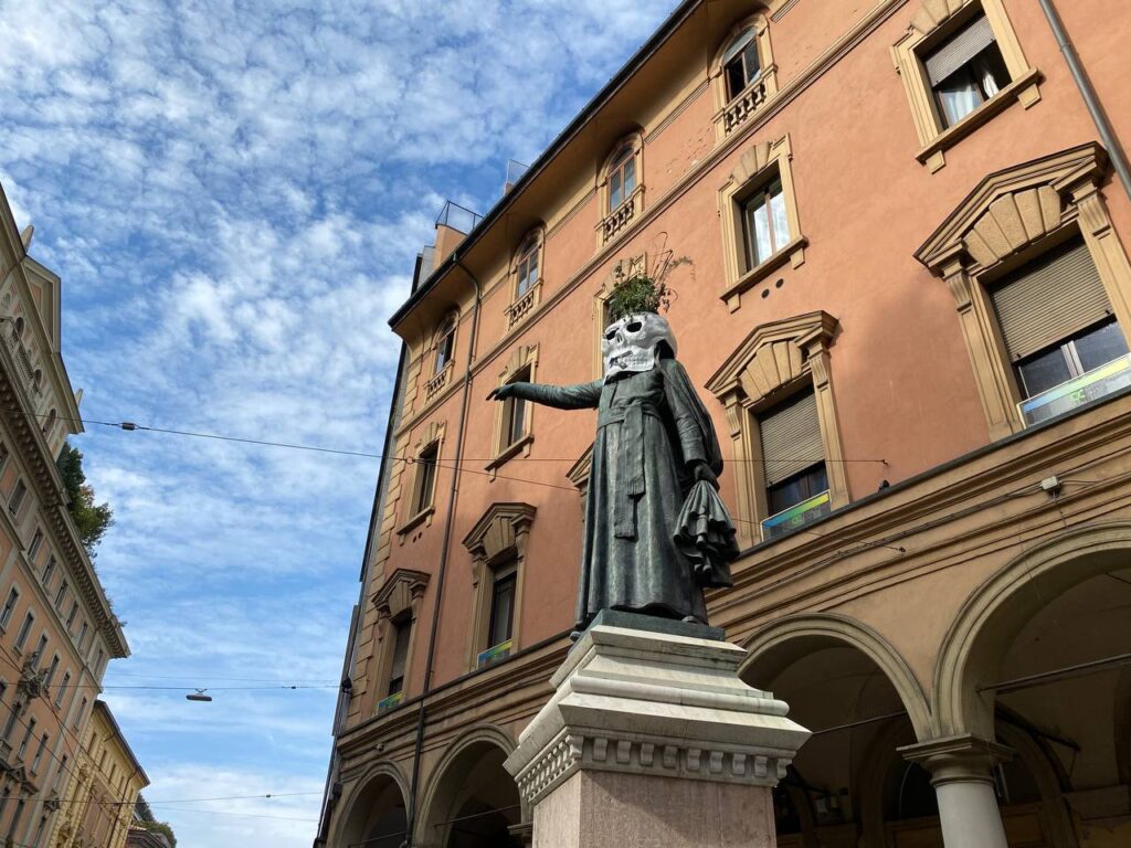 Maschere di cartapesta sulle statue di Ugo Bassi e Luigi Galvani