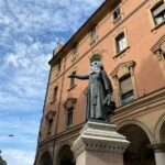 Maschere di cartapesta sulle statue di Ugo Bassi e Luigi Galvani